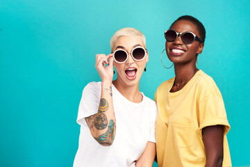 The future sure is looking bright. Studio shot of two young women wearing sunglasses against a turquoise background. - obrazy, fototapety, plakaty