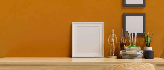 Wooden table top with blank picture frame mockup over modern stylish orange wall.