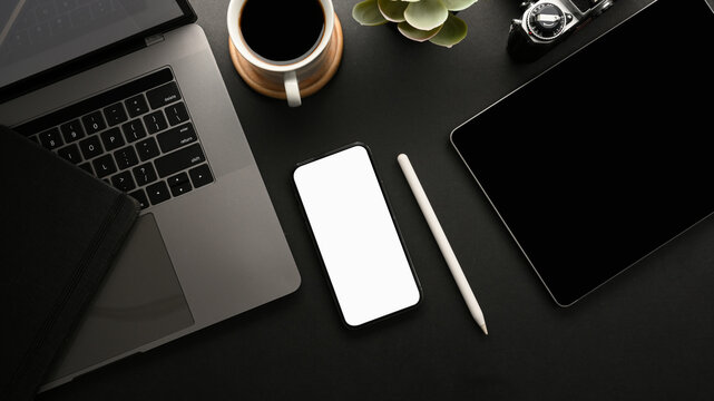 Modern dark workspace with digital devices and smartphone mockup.