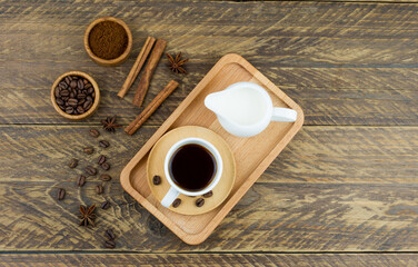 top view of the wooden tray with expresso cup, coffee assortment and milkman with milk. brown wood...