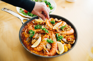 パエリアにレモンを添える男性の手