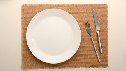 Simple dining table setting with white ceramic plate and silver cutlery