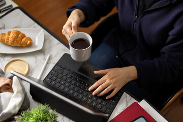 Businesswoman sipping coffee while working on digital tablet computer
