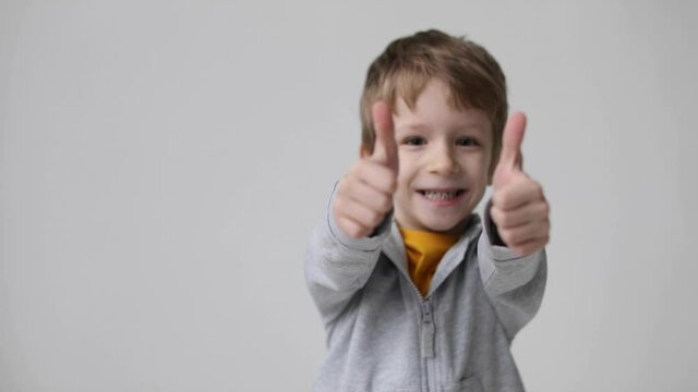 Cute little boy shows thumbs up gesture, happy facial expression emotion