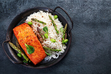 Baked salmon with rice and asparagus on gray background.