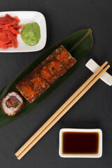 tuna rolls lie on a bamboo leaf next to the sauce, top view