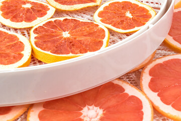 slices of red grapefruit lie on drying trays