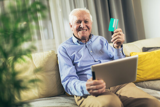 Senior man grandfather shopping online with tablet and credit card at home.