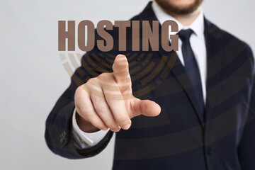 Businessman pointing at word HOSTING on virtual screen against light background, focus on hand