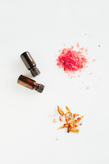 Skin care products - sea aromatic bath salt, essential oil and orange flowers lie on a white background