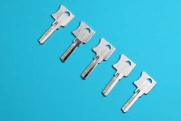 Door metal keys are arranged in a line on a colored watercolor paper background. Flat lay concept.