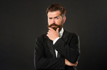 bearded businessman in tuxedo on black background, fashionist