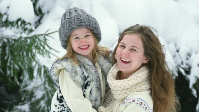 Happy Family Hug. Mom Hold Daughter Smile In Arms Winter Forest. Two Sisters Walk Among White Snow. Walks Outside. Winter Games In Garden Christmas And New Year. Portrait Fun Caucasian Woman And Girl.