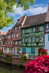 Flower beds along the city canal in the center of the medieval city of Colmar. Floral decoration of an ancient city. Alsace, France