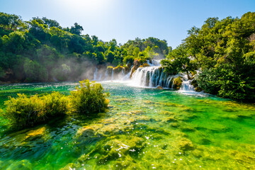 Waterfalls at Skradinski Buk, national nature park Krka, Croatia. Flowing water in beautiful nature, green plants and trees. Sunny summer day.