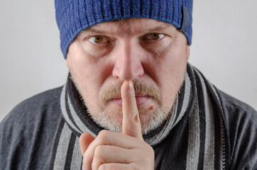 A adult male holds his finger to his lips. A gesture of silence - obrazy, fototapety, plakaty