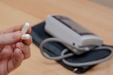 A mature man holds two white medicine pills in his hand.