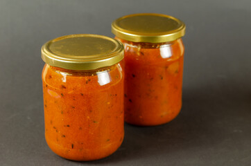 Hippophae jam in a glass jar with the lid on gray background.