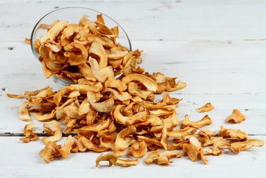 Homemade dried apples in a bowl. Dehydrated  apple chips without peels on the white wooden table.