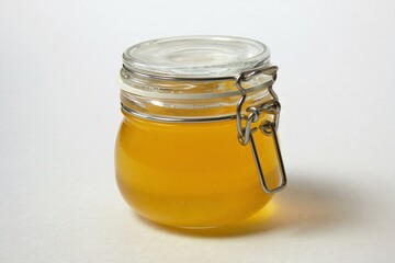 Isolated closed glass jar of honey on a white background. Close-up.