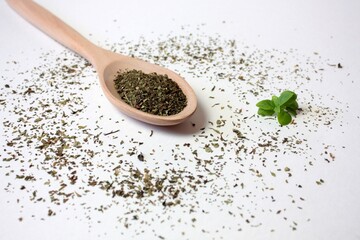 Dry basil (seasoning) in a wooden spoon on a white background.