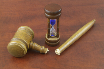 Broken wooden judge gave and hourglass, not working legal system and time concept.