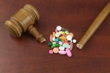 Not working laws and medicine concept. Heap of drugs and broken judge gavel.