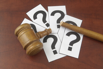 Changing legal system, laws and court concept. Broken wooden judge gavel on question marks.