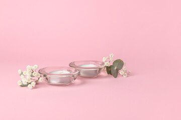 Candles with glass holder and flowers on pink background