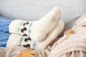 Woman in warm socks lying on sofa at home, closeup