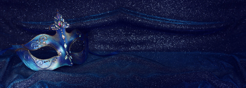 Photo of elegant and delicate Venetian mask over blue dark silk background