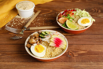 Healthy quinoa bowls with egg and meat on wooden background