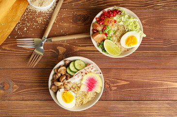 Healthy quinoa bowls with egg and meat on wooden background
