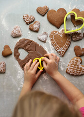 girl makes gingerbread cookies in shape of heart of dough