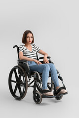 Fototapeta na wymiar Young woman in wheelchair on light background