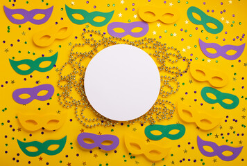 Mardi Gras Masquerade festival carnival masks, gold color beads and golden, green, purple confetti on yellow background.