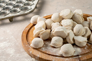 Russian dumplings on a round board. Raw ravioli before cooking.