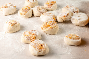 Dough with meat in the shape of a snail. Raw close-up, selective focus, white table.