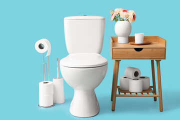 Fototapeta na wymiar Toilet bowl, holder with rolls of paper and table on blue background