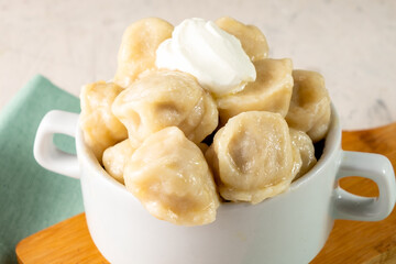 Boiled dumplings with sour cream close-up. Russian traditional dumplings.