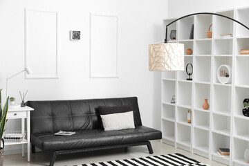 Interior of modern living room with black couch, big shelving unit and lamps