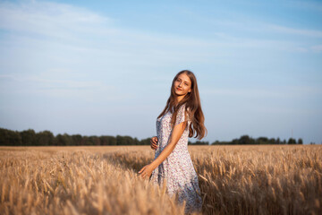 Naklejka premium Portrait of a girl in ripe field of rye at sunset