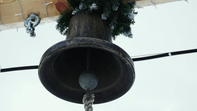 The ringer pulls the rope of a bronze bell.