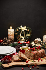 Traditional French terrine covered with bacon on dark wooden background with Christmas decorations