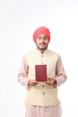 Indian farmer using diary on white background.