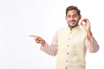 young indian man in traditional wear and showing direction on white background.