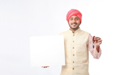 Indian man holding white board, promoting offers on festival season while wearing traditional cloths, standing over white background.