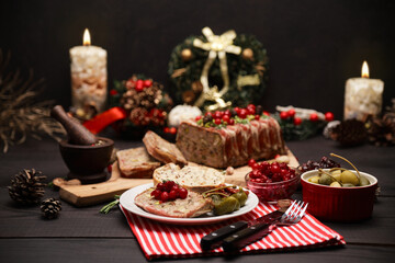 Traditional French terrine covered with bacon on dark wooden background with Christmas decorations
