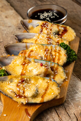 Baked mussels with cheese and teriyaki sauce. Vertical photo. Close-up.