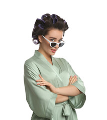 Happy young woman in silk bathrobe with hair curlers and sunglasses on white background